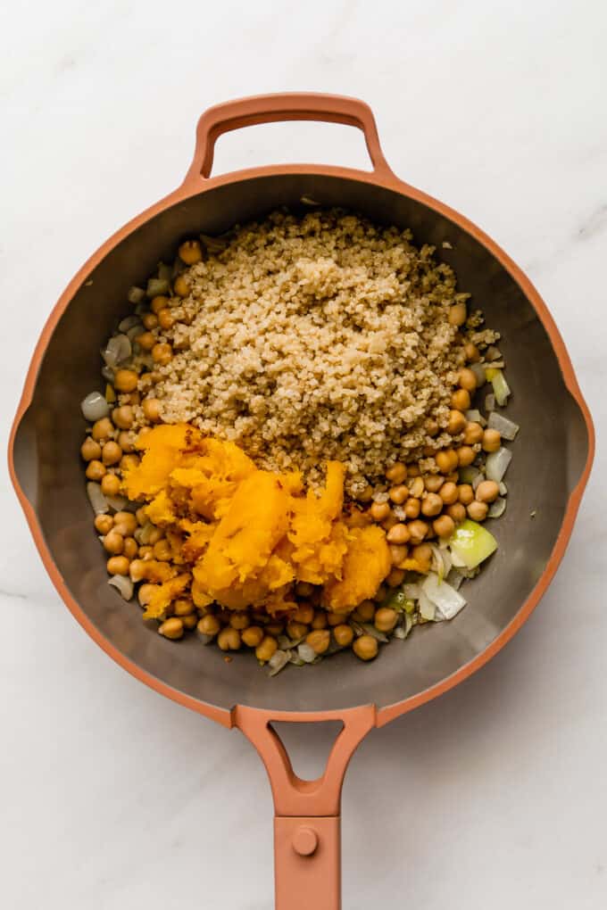 quinoa, chickpeas, acorn squash and onion in a pink pan