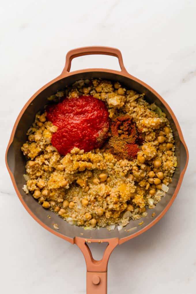 chickpeas, quinoa, spices and tomato sauce in a pink pan
