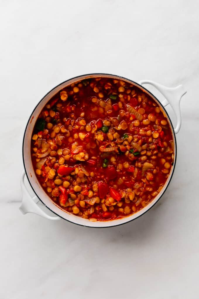 cooked lentils and veggies in a tomato sauce in a white pot