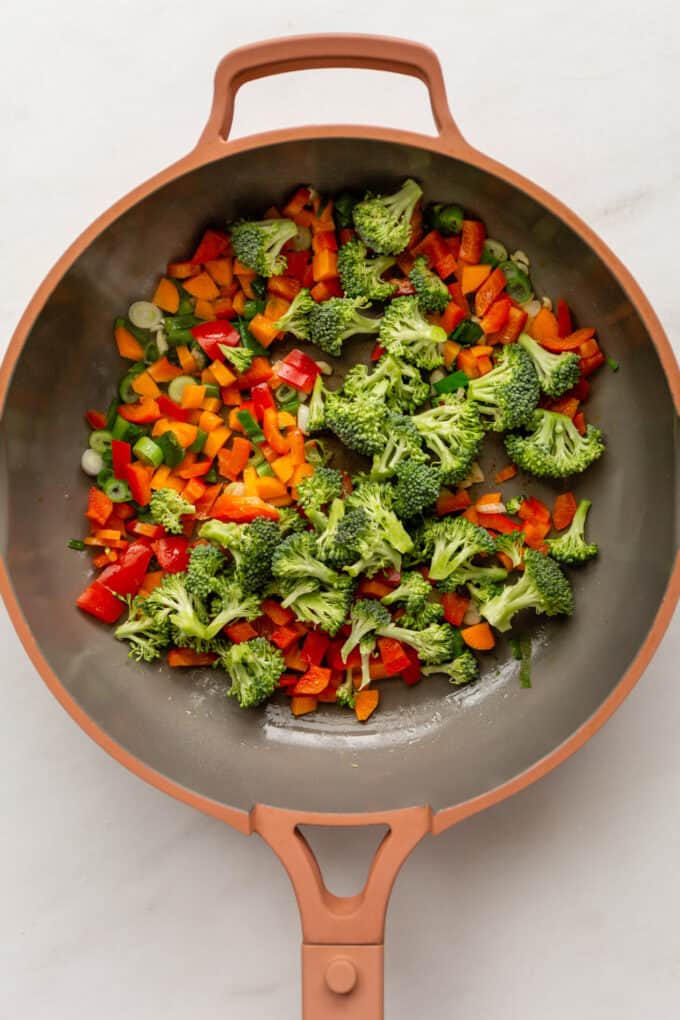 broccoli, peppers, carrots and scallions in a pink pan