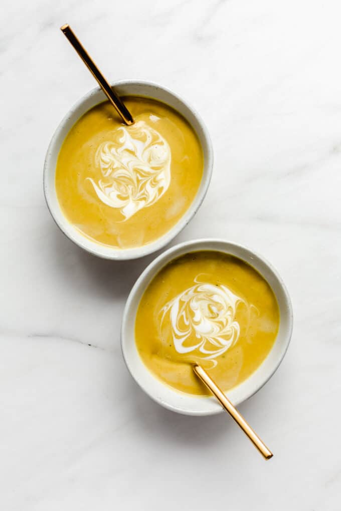 two bowls of curried cauliflower soup topped with coconut milk