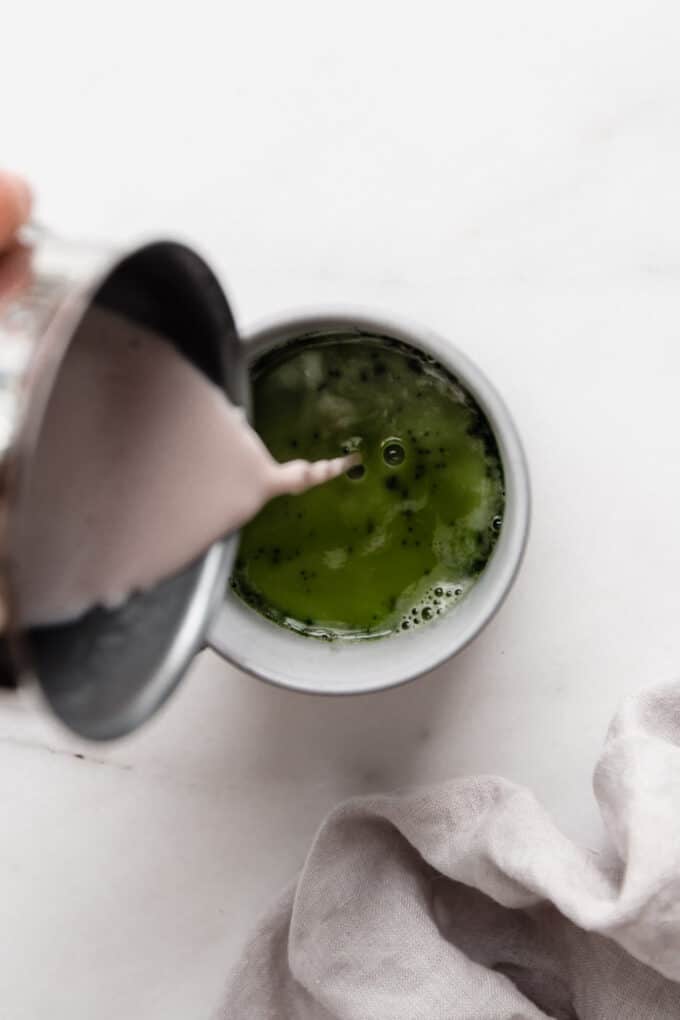 milk being poured into a cup of matcha tea