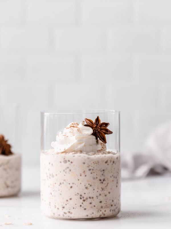 chai latte overnight oats in a cup topped with whipped cream and star anise