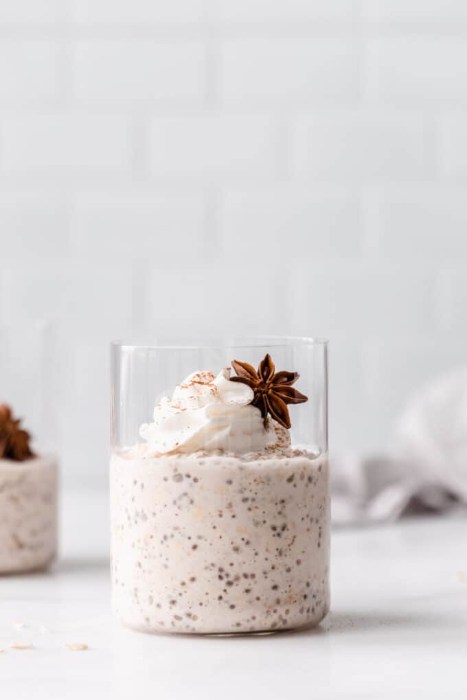 chai latte overnight oats in a cup topped with whipped cream and star anise