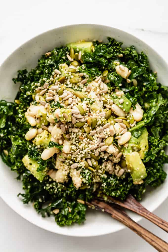 Kale and white bean salad in a bowl with two wood serving spoons