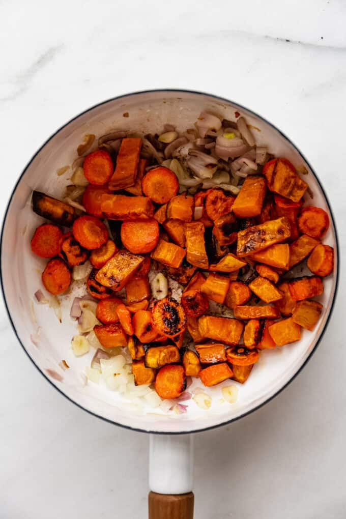 onion, garlic, ginger, roasted sweet potatoes and carrots in a pot