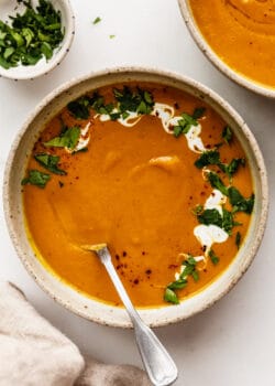 A bowl of sweet potato carrot and ginger soup topped with cilantro and yogurt
