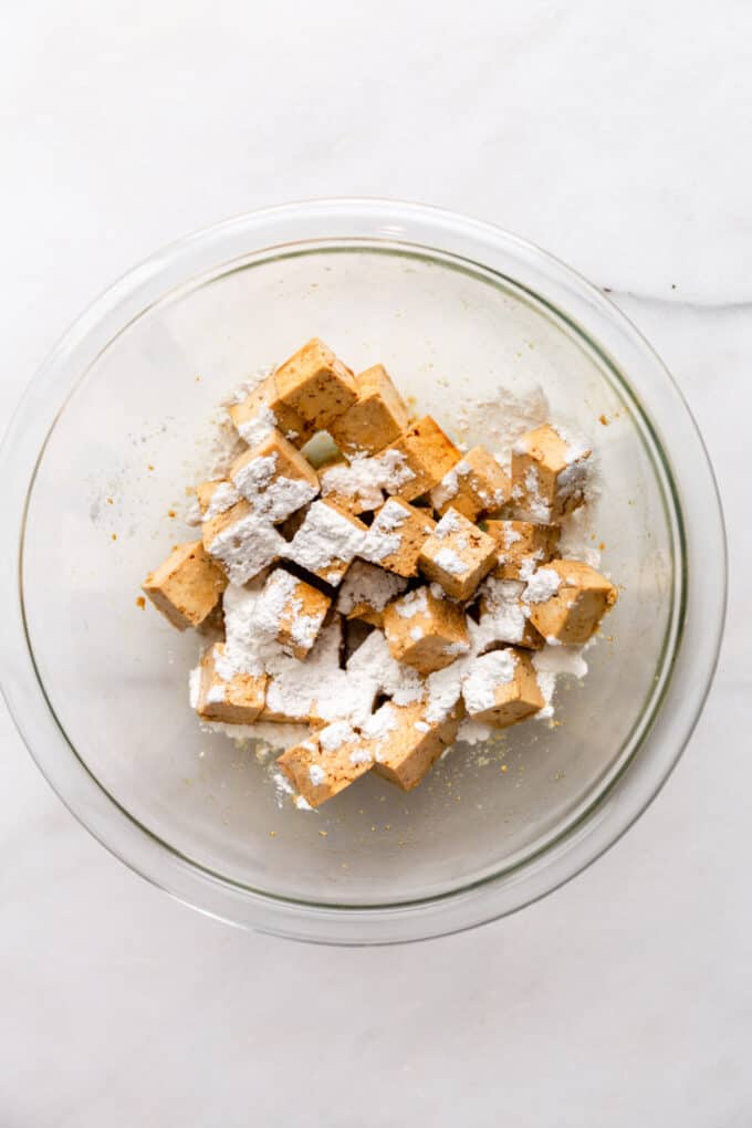 cubes of tofu in a mixing bowl with cornstarch sprinkled on top