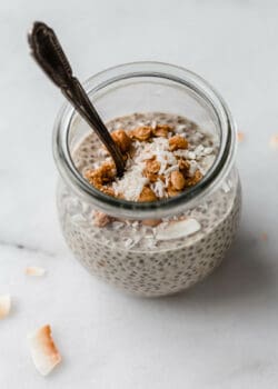 a jar of peanut butter chia pudding topped with shredded coconut and granola