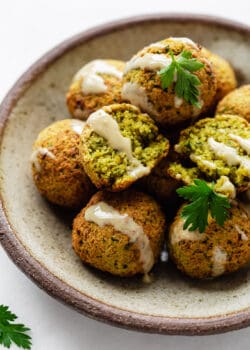 falafel on a ceramic plate drizzled with tahini