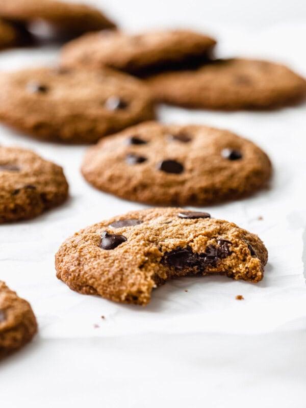 almond flour chocolate chip cookies on parchment paper with a bite taken out of one