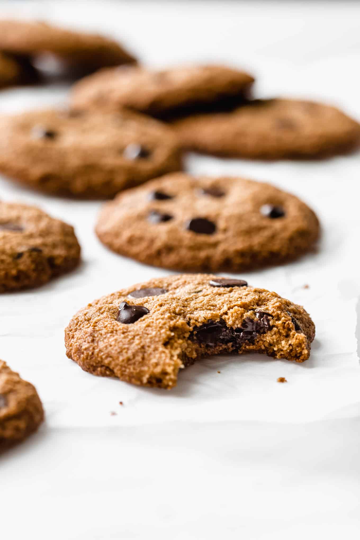 almond flour chocolate chip cookies on parchment paper with a bite taken out of one
