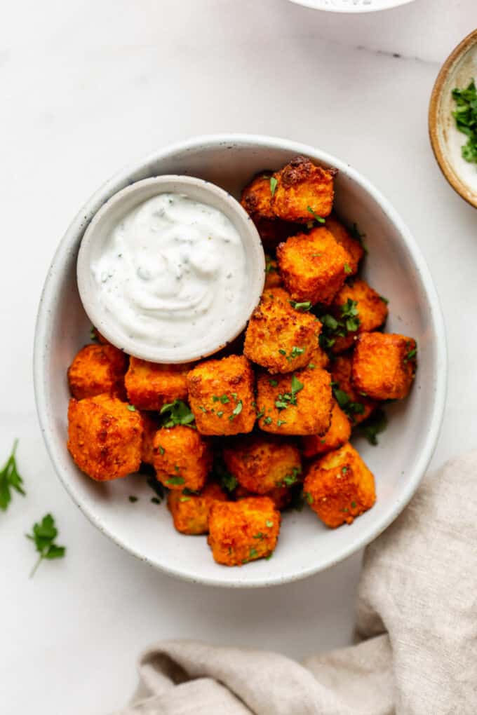 a bowl of buffalo tofu with a small bowl of ranch sauce