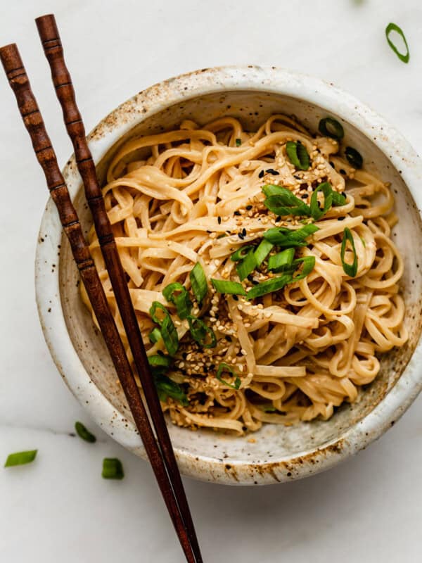 sesame noodles in a bowl with wood chopsticks