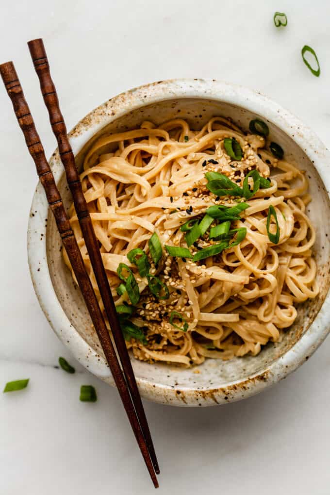 sesame noodles in a bowl with wood chopsticks