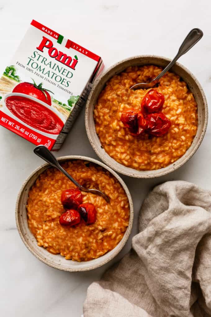 two bowls of tomato risotto with strained tomatoes on the side