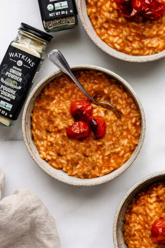 three bowls of tomato risotto with onion powder on the side
