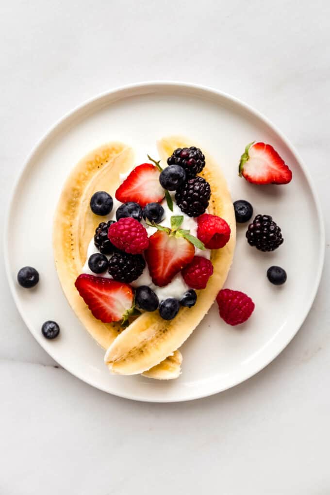 a sliced banana with yogurt and berries