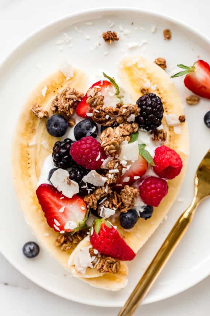 breakfast banana split with yogurt and berries on a plate
