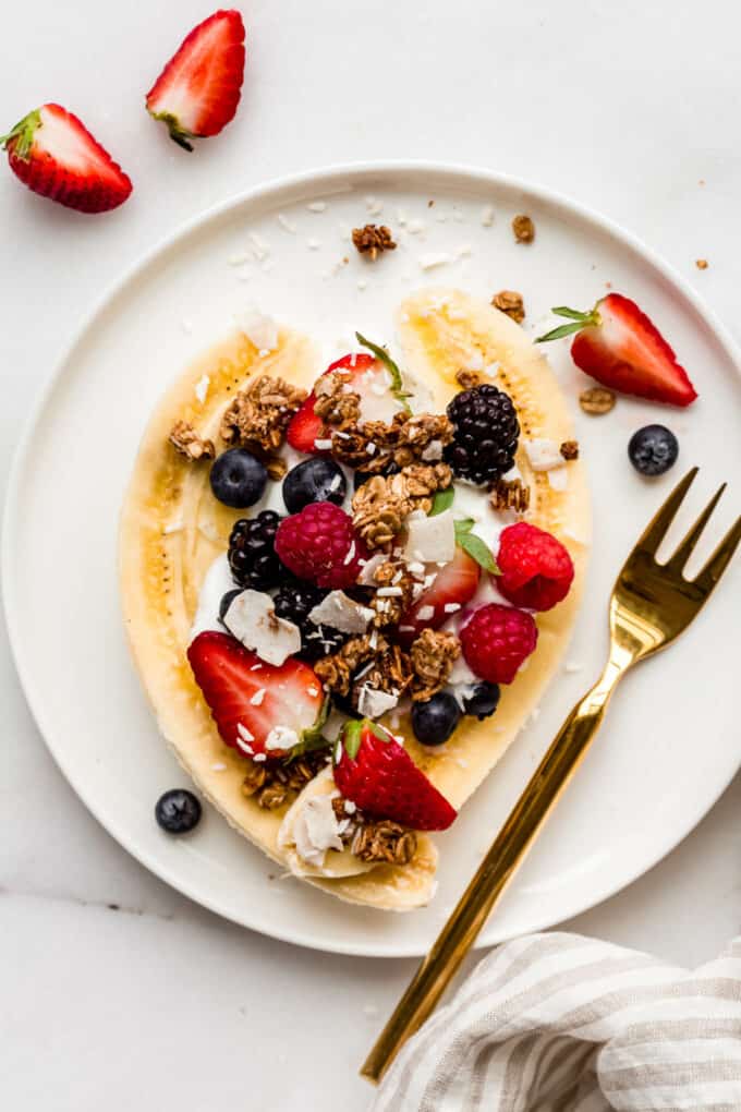 a breakfast banana split with berries, granola and coconut