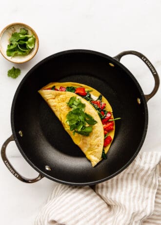 a chickpea flour omelette in a black pan with a striped napkin on the side