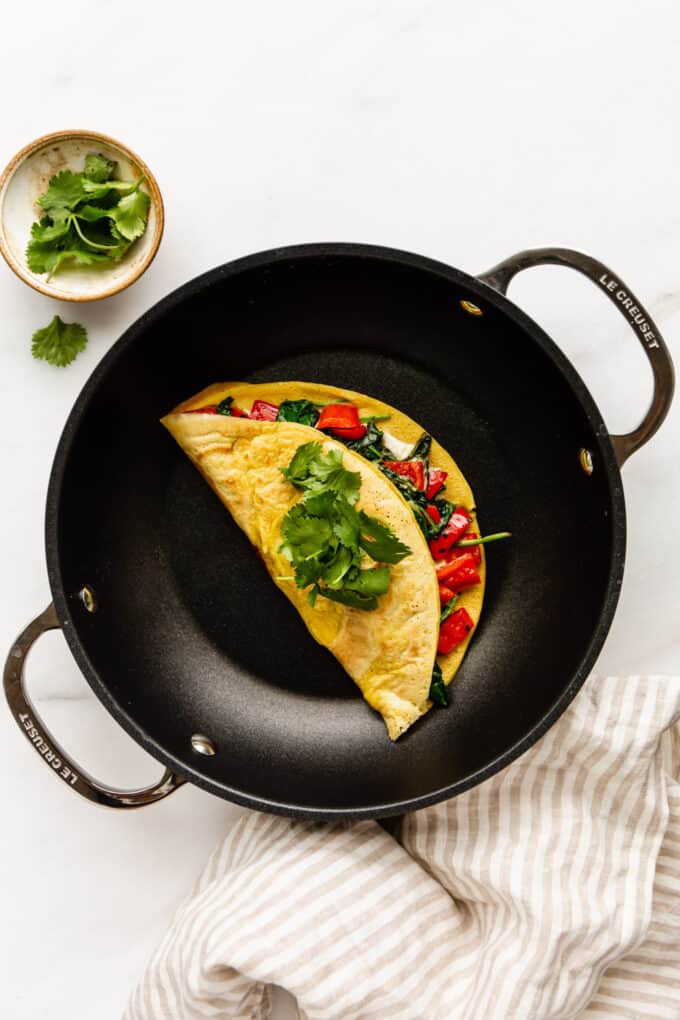 a chickpea flour omelette in a black pan with a striped napkin on the side