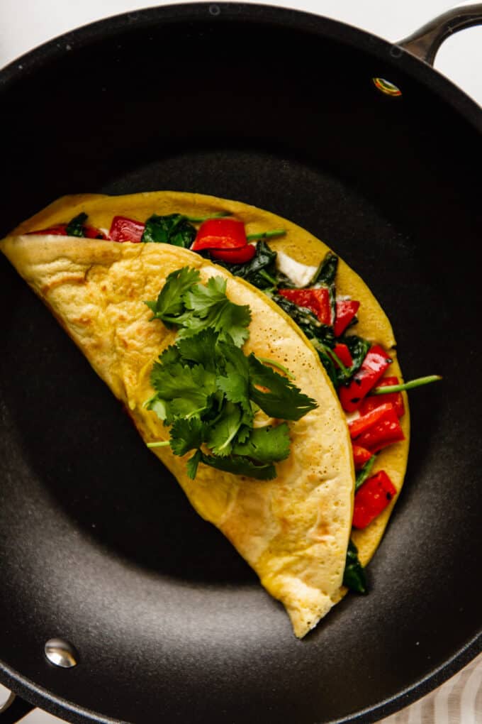 a chickpea flour omelette stuffed with peppers and spinach in a pan