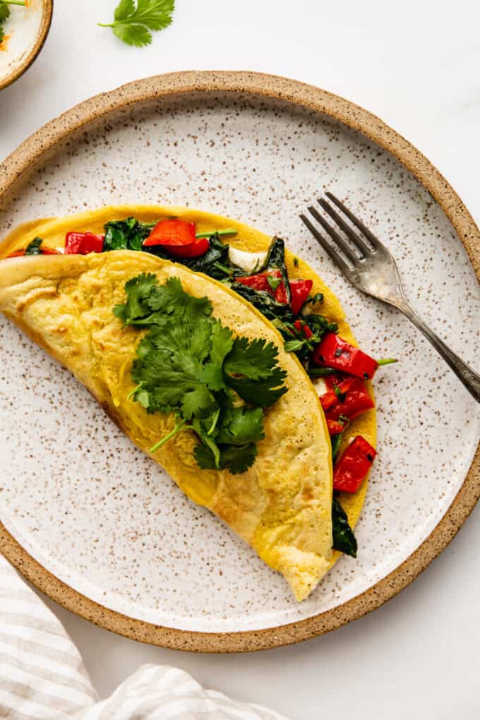 a chickpea flour omlette stuffed with peppers and spinach on a ceramic plate