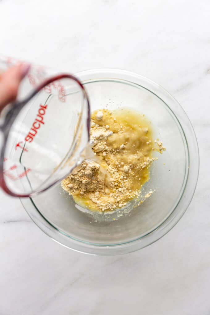water being poured into a bowl of chickpea flour