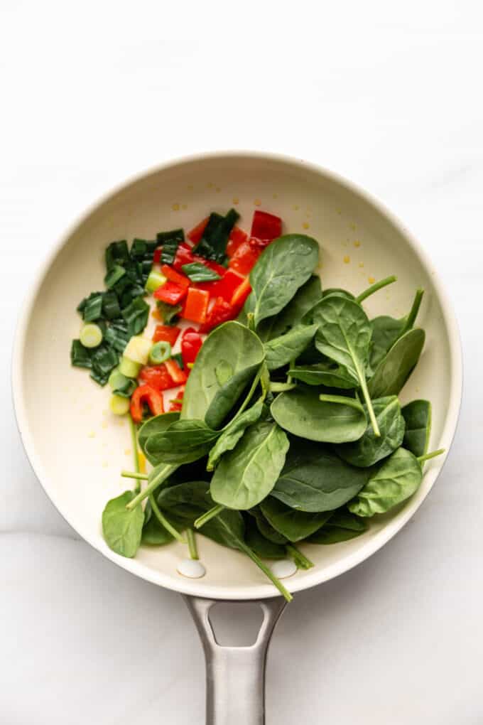 spinach, peppers and green onion in a pan
