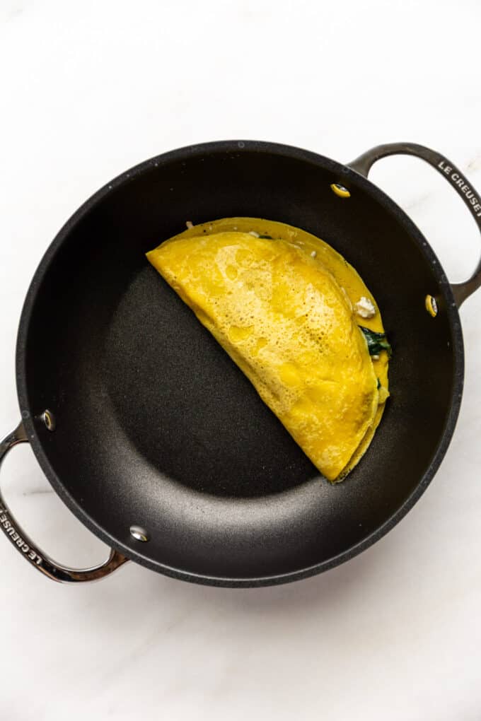 a chickpea flour omelette cooking in a black pan