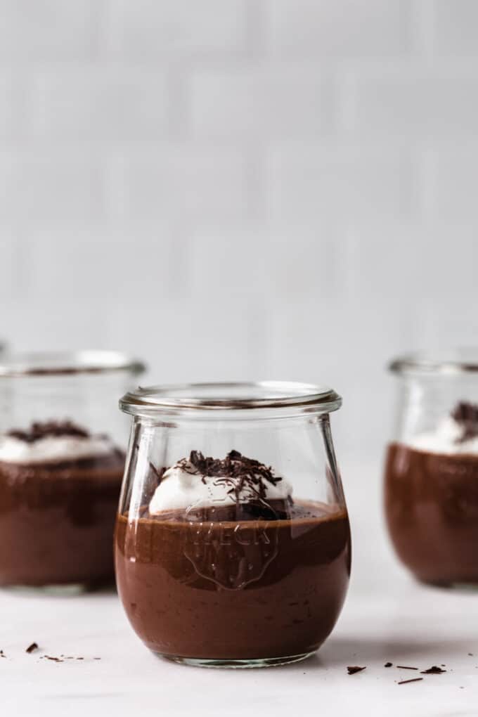 three cups of vegan chocolate pudding on a marble counter