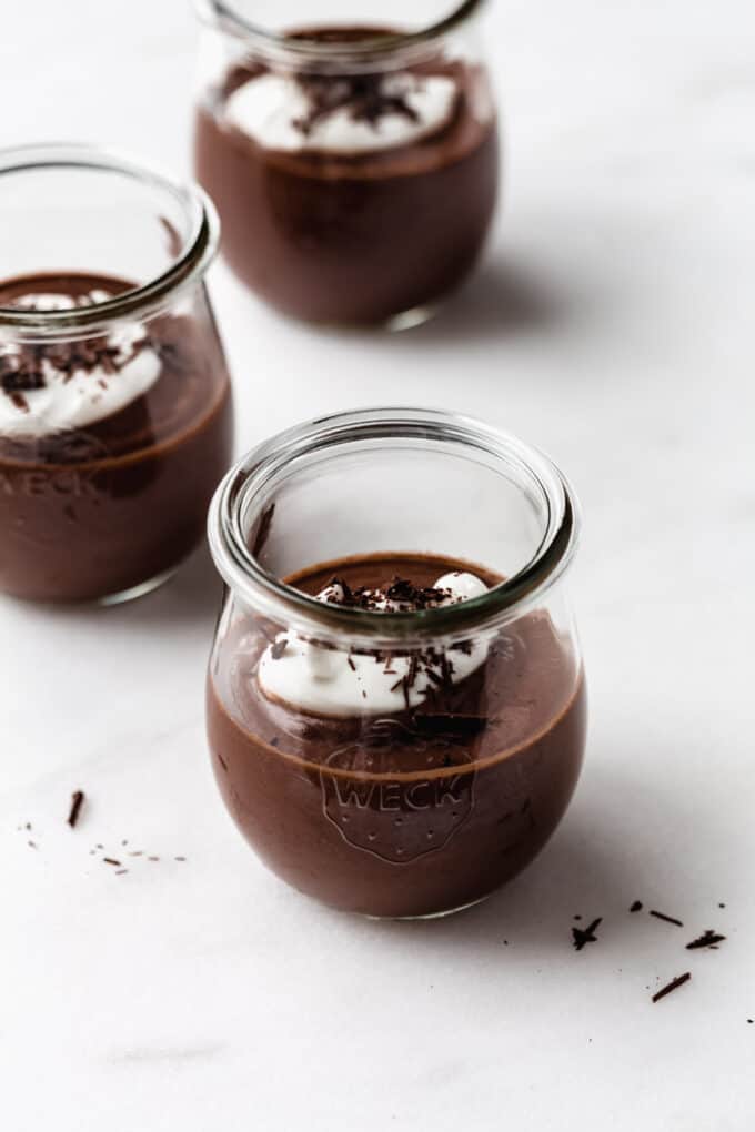 three cups of vegan chocolate pudding topped with yogurt