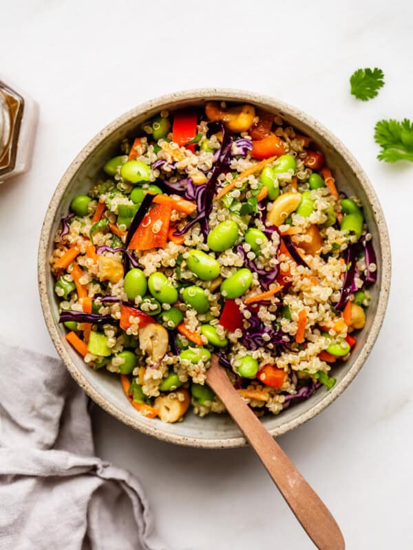 A bowl of edamame salad with a wood spoon in it
