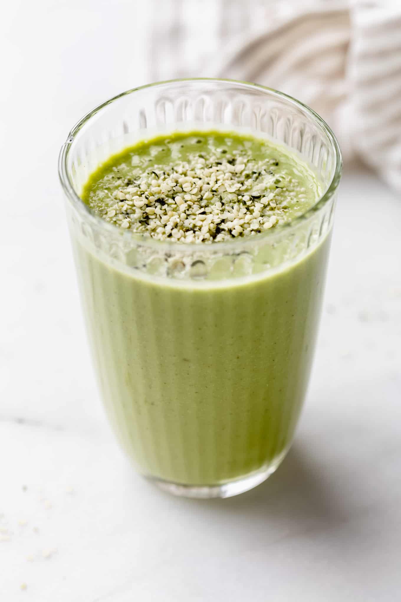 A green smoothie in a glass topped with hemp seeds