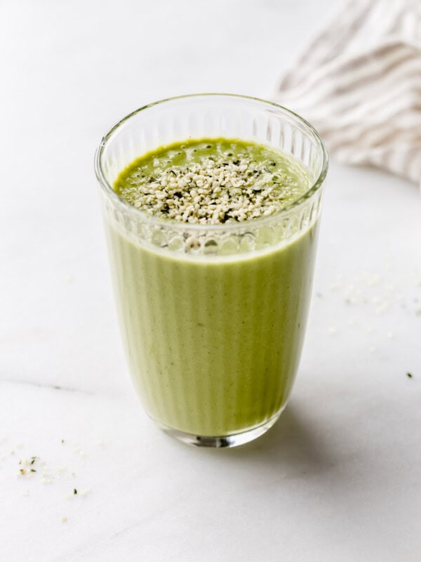 A glass of green protein smoothie with a beige napkin on the side