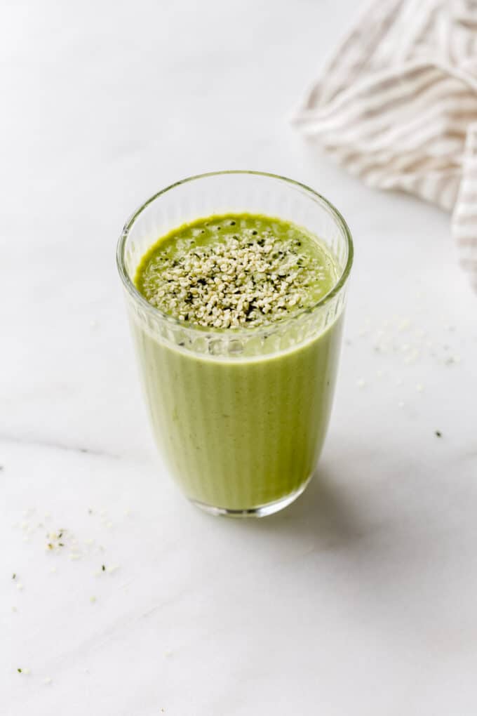 A green protein smoothie topped with hemp seeds in a glass