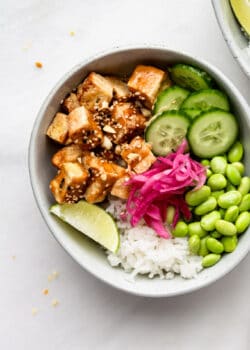 a peanut tofu bowl with cucumber, edamame and pickled onions
