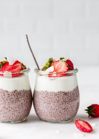 two jars of strawberry chia seed pudding topped with strawberries