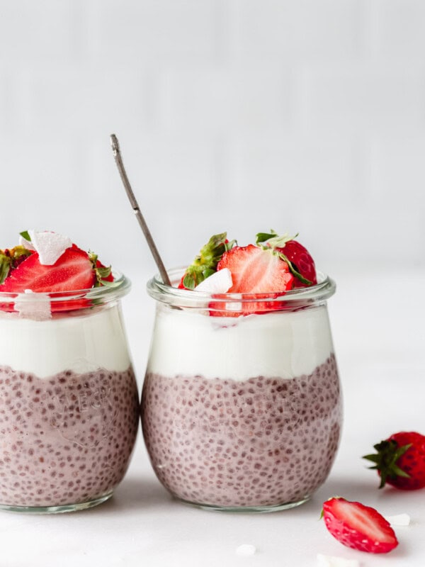 two jars of strawberry chia seed pudding topped with strawberries