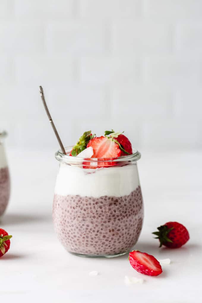 a jar of strawberry chia pudding topped with yogurt and strawberries