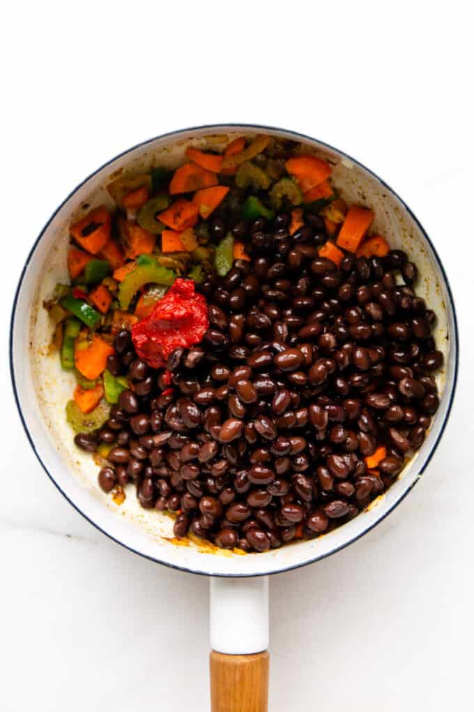 vegetables, tomato paste and black beans in a white pot