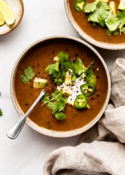 two bowls of black bean soup with a beige napkin on the side