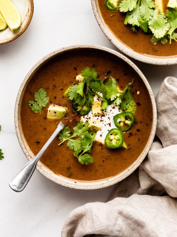 two bowls of black bean soup with a beige napkin on the side