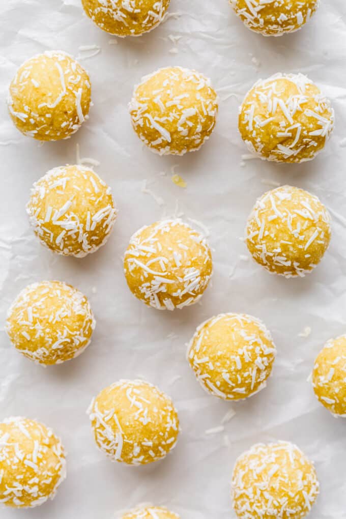 lemon bliss balls rolled in shredded coconut on parchment paper