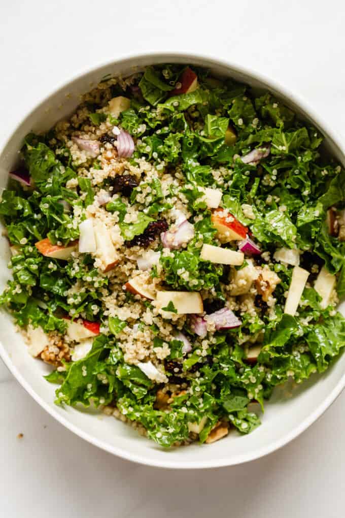 a bowl of quinoa salad with kale and apples