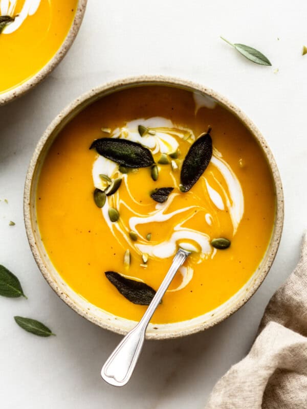a bowl of acorn squash soup with fried sage and pumpkin seeds