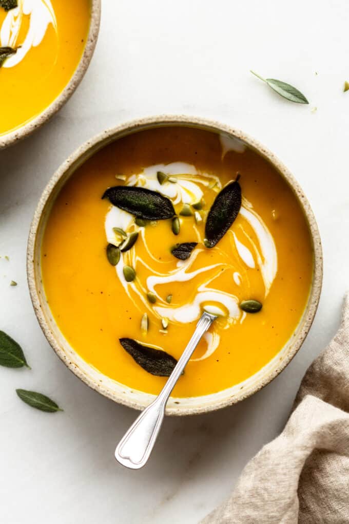 a bowl of acorn squash soup with fried sage and pumpkin seeds