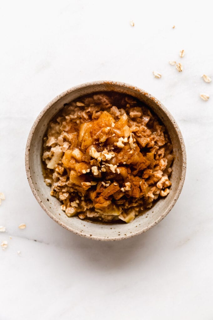 apple pie oatmeal in a bowl topped with walnuts