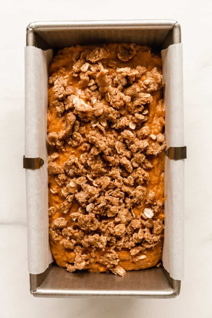 pumpkin banana bread batter with streusel topping in a loaf pan